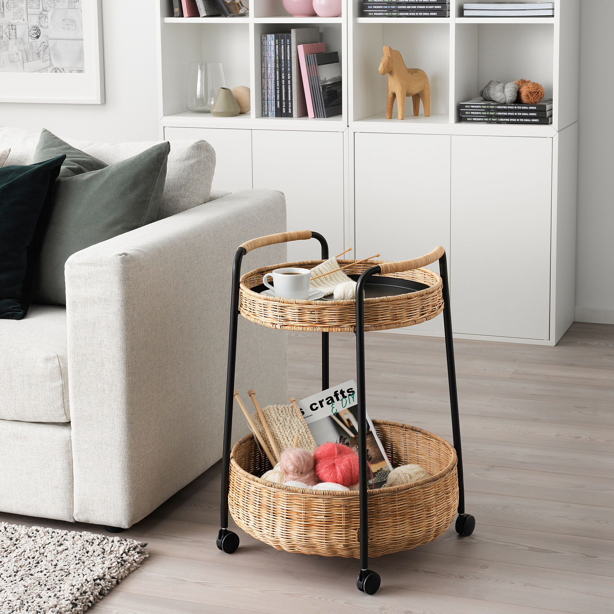 LUBBAN wicker trolley near grey sofa, holding yarn & coffee, fits cozy space.