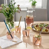 Pink drinks with lemon, rosemary, and straws; salad, flowers.