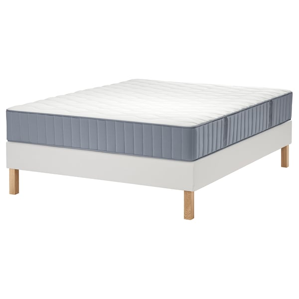 White LYNGÖR bed with blue-grey mattress, wooden legs, quilted top.