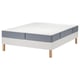 A white LYNGÖR bed base with a gray vesteröy mattress. It has wooden legs and a pocket spring design.