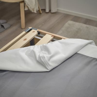 Wooden bed frame with removable, washable cover showing slatted design.