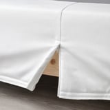 A white LYNGÖR mattress base with a removable, washable cover and flat slats supporting a spring core.