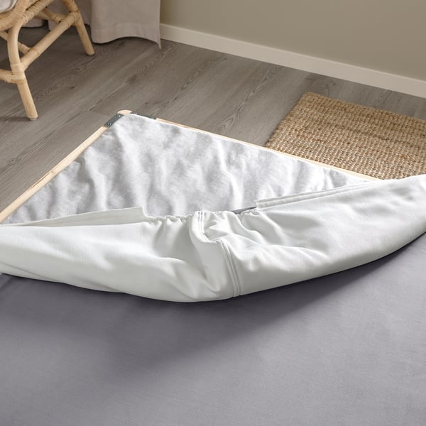 Gray mattress cover on wooden slats, part of LYNGÖR bed base, ready for assembly.