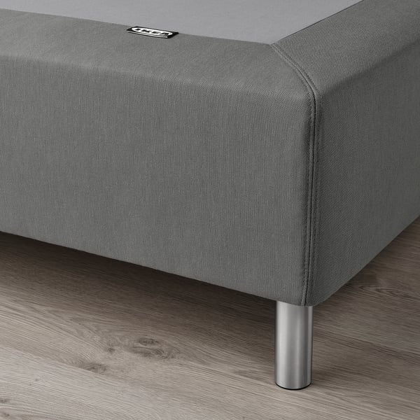 Gray fabric bed base with stainless steel legs, supporting mattress evenly.