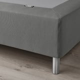 Gray fabric bed base with stainless steel legs, supporting mattress evenly.
