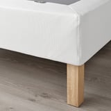Close-up of LYNGÖR bed base corner, showing flat slats supporting mattress, with wooden legs.