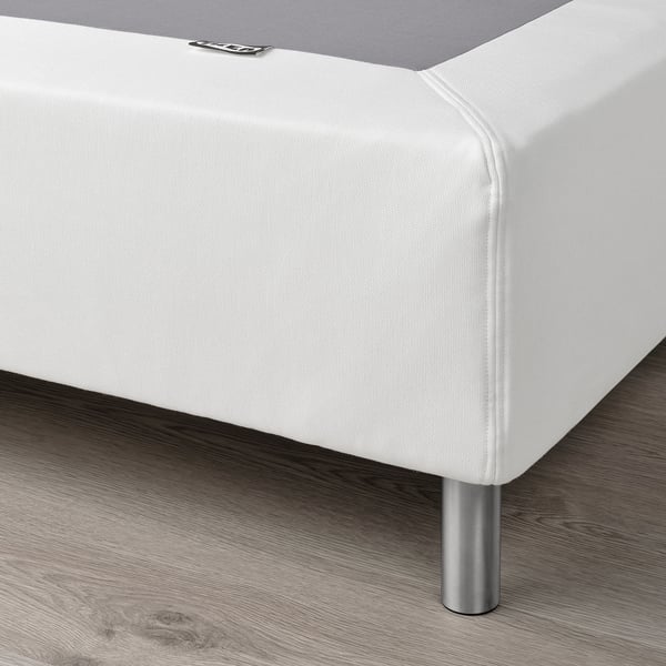 Close-up of modern white LYNGÖR platform bed base with metal legs, showing sleek design and support structure.