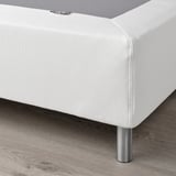 Close-up of modern white LYNGÖR platform bed base with metal legs, showing sleek design and support structure.