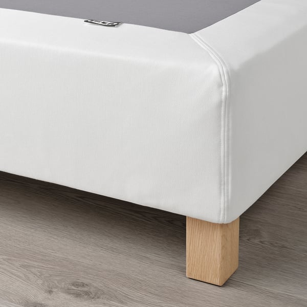 White mattress base with wooden legs. Supports mattress, reduces pressure, and allows air circulation.