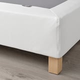 White mattress base with wooden legs. Supports mattress, reduces pressure, and allows air circulation.