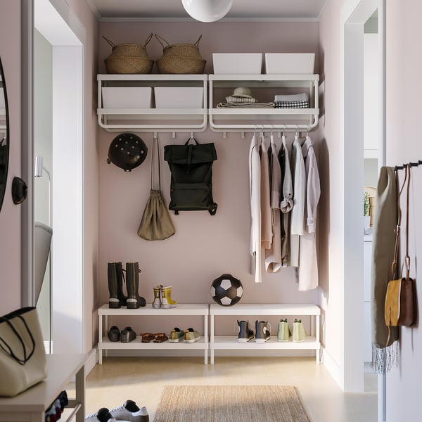 Organized closet with white MACKAPÄR shelves, holding baskets, bags, and clothes.