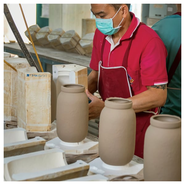 Person crafting earthy-toned, hand-shaped, minimalist MÄVINN vase from stoneware in a workshop.
