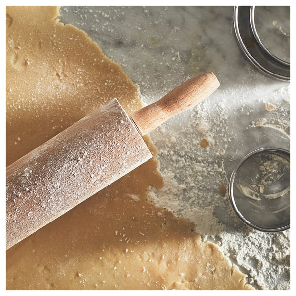 Rolling pin on floured gray counter with dough bits. Wood handle, metal rod. Part of MAGASIN baking set.