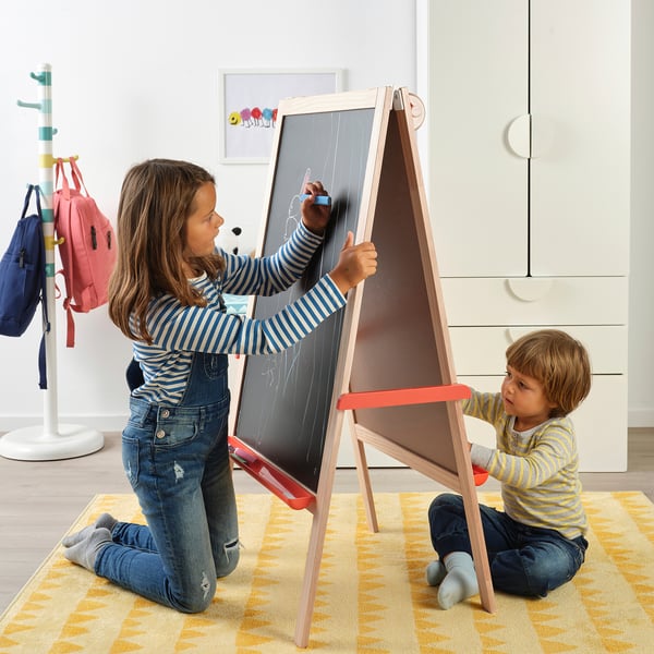 Two kids draw on a two-sided chalkboard. One stands, one kneels, using big, easy-to-grip chalks.