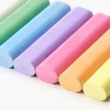 Six vibrant, large pastel-colored chalks neatly arranged in a row, showcasing their smooth texture and bright hues, ideal for drawing.