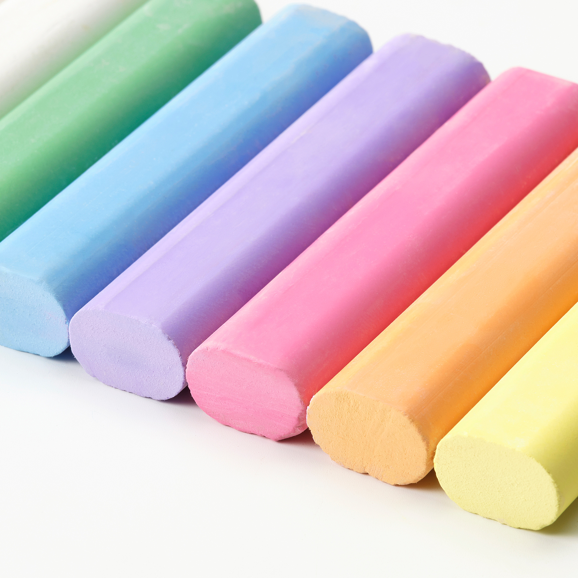 Six vibrant, large pastel-colored chalks neatly arranged in a row, showcasing their smooth texture and bright hues, ideal for drawing.
