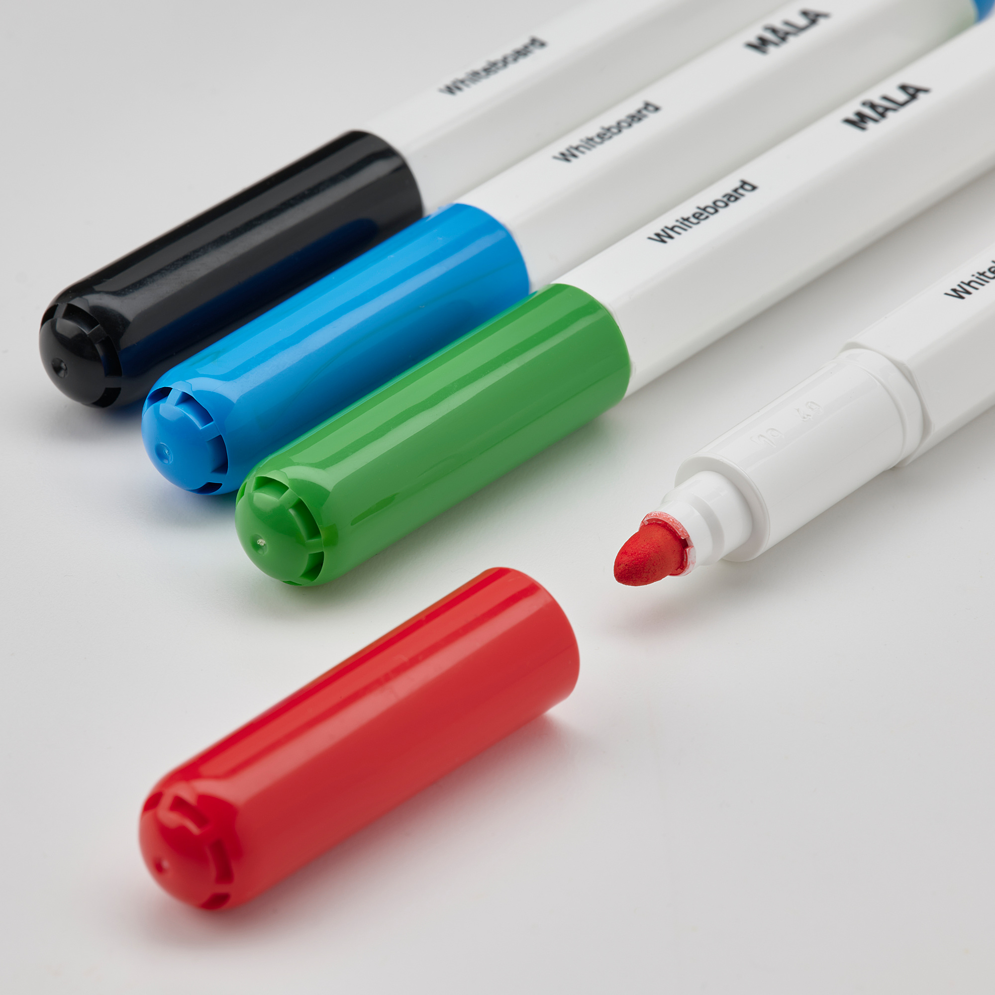 Image description: four colorful markers and an eraser. Markers are blue, green, black, and red, with a white eraser tipped in red.