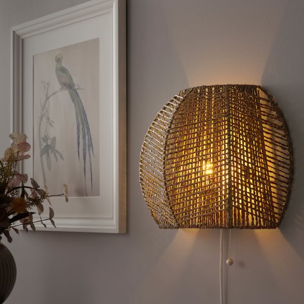 A wall-mounted lamp with a woven natural material shade casts light in multiple directions, creating a warm and cozy atmosphere.