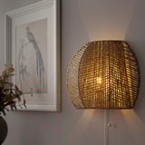 A wall-mounted lamp with a woven natural material shade casts light in multiple directions, creating a warm and cozy atmosphere.