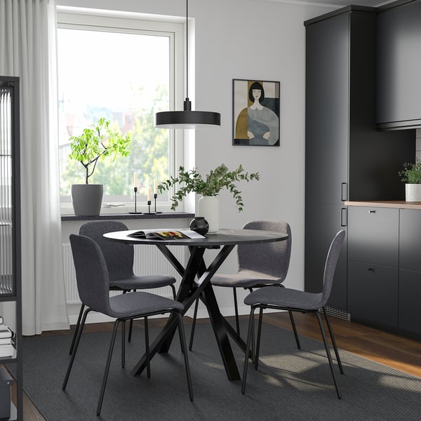 Modern dining setup with MARIEDAMM round table & grey chairs. Dark frames contrast light walls. Small size, centered under pendant light.