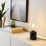 MARKFROST table lamp with black marble base and clear bulb on storage unit, beside books, green vase, and plant.