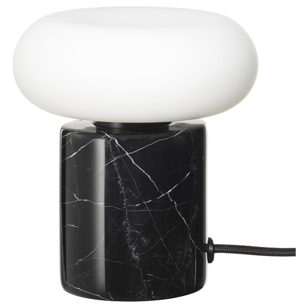 The MARKFROST lamp a black marble base and a frosted glass shade, emitting warm, soft light.