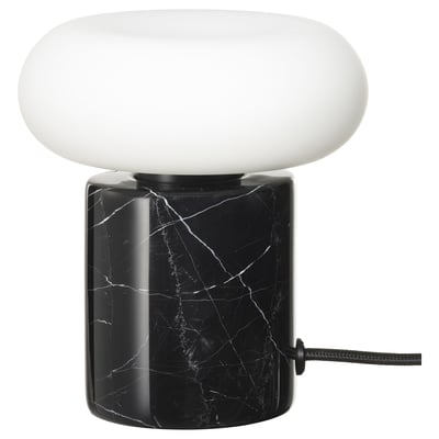 The MARKFROST lamp a black marble base and a frosted glass shade, emitting warm, soft light.