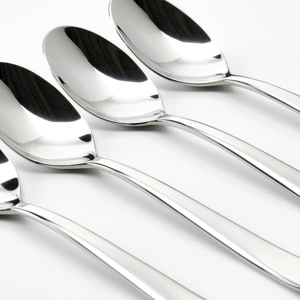 Four gleaming, polished stainless steel spoons arranged neatly in a row, reflecting light, showcasing high-quality craftsmanship.
