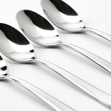 Four gleaming, polished stainless steel spoons arranged neatly in a row, reflecting light, showcasing high-quality craftsmanship.
