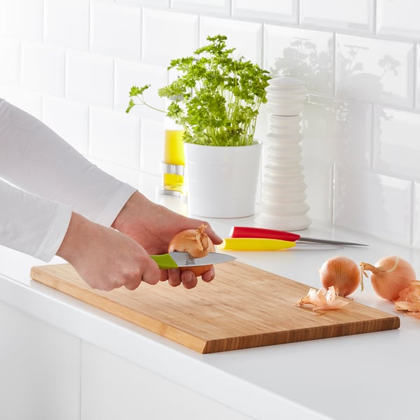 Person chops onion on wooden cutting board in kitchen.