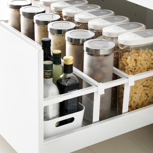 White drawer organizer with clear containers, bottles, and a small basket, showcasing efficient storage.