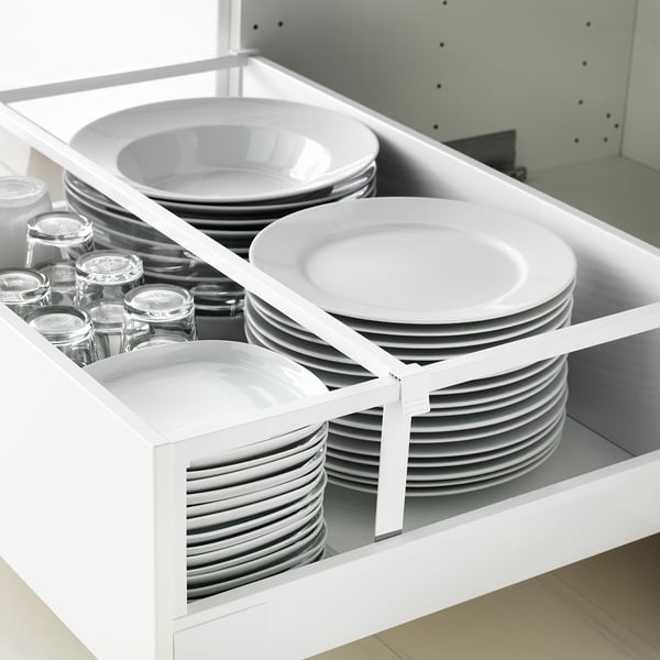 Organized kitchen drawer with white plates, bowls, and glass jars. MAXIMERA drawer system pulls fully out with a soft-close feature.
