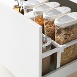 Open kitchen drawer with clear cereal containers; modern design with quiet-close feature.