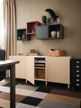 Modern room with MEJARP storage units: light wooden cabinet, black shelves, decorative items, colorful rug.