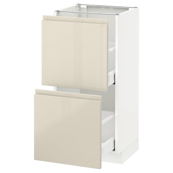 A white METOD kitchen cabinet with two beige drawers. The drawers have a glossy finish and sleek design.