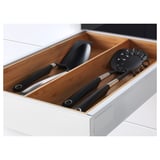 Wooden drawer in white cabinet holds black kitchen utensils: ladle, turner, and whisk, organized and ready for use.