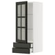 A modern, white METOD kitchen cabinet with black bodbyn glass doors. The cabinet includes two pull-out drawers and adjustable shelves.