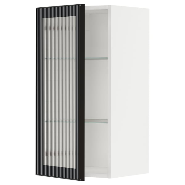 This image shows a modern, white METOD kitchen cabinet with a black reeded glass door. It is sleek and contemporary, designed for kitchen storage.