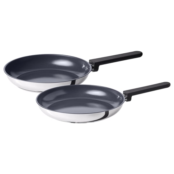 Two black-handled frying pans of different sizes, shiny silver with dark interiors, placed side by side.