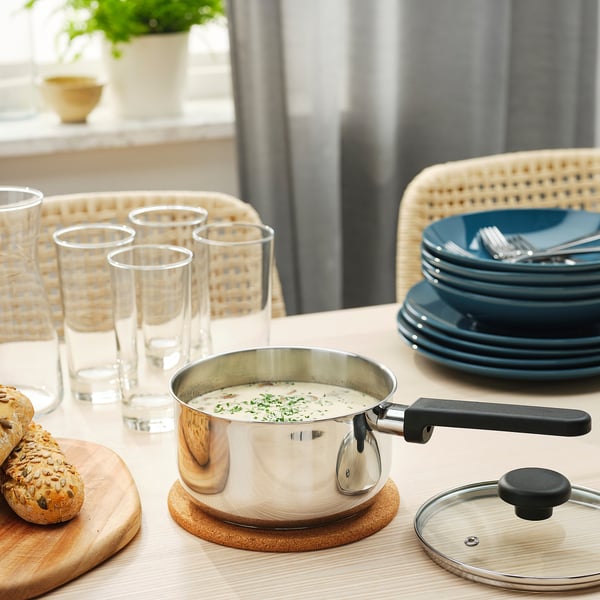 Table set with MIDDAGSMAT saucepan, bread, plates, and glasses, ready for a meal.
