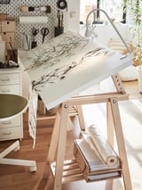 Art studio with MITTBACK wooden easel displaying abstract line drawing, near desk with supplies.