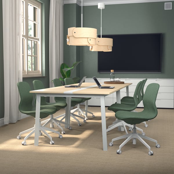 Modern conference table, MITTZON, light wood, rectangular, with green chairs, perfect for meetings, flanked by large windows.