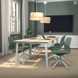 Modern conference table, MITTZON, light wood, rectangular, with green chairs, perfect for meetings, flanked by large windows.