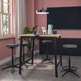 MITTZON conference table set with black stools, grey cushions, wooden top, black pendant lamp, red-pink walls, large window, black tv.