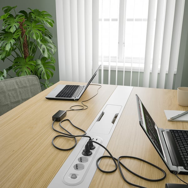 Conference table with laptops and power outlets, suitable for meetings and work.