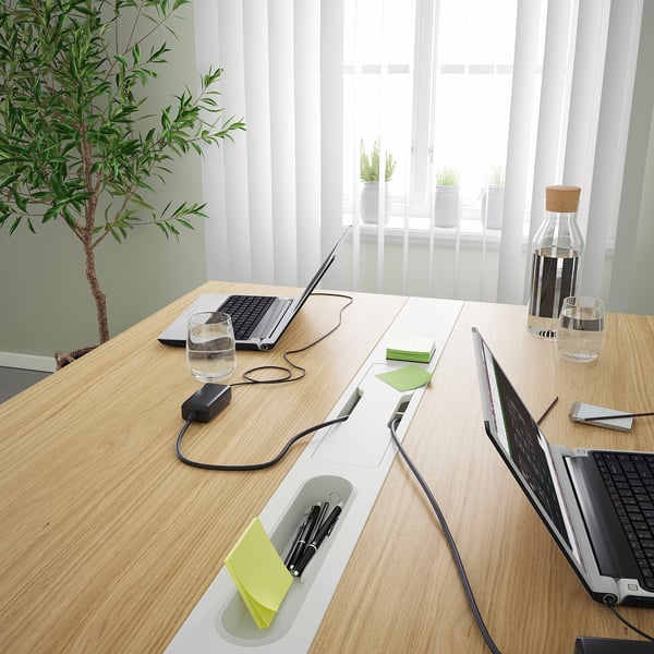 Conference table with cable trays, water glasses, plant, and blinds.
