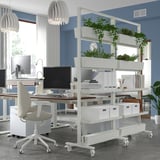 Modern workspace with MITTZON mobile plant stand, desk, chairs, computers, and lamps.