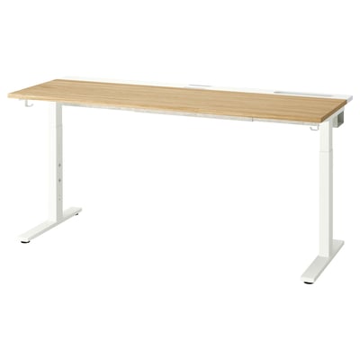 A MITTZON desk with a light wood top and white legs. Its height-adjustable and cable management.