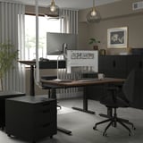 MITTZON black sit-stand desk with dual motors, ergonomic chair, plush rug, and pendant lights. Modern design, ample size for multiple items.