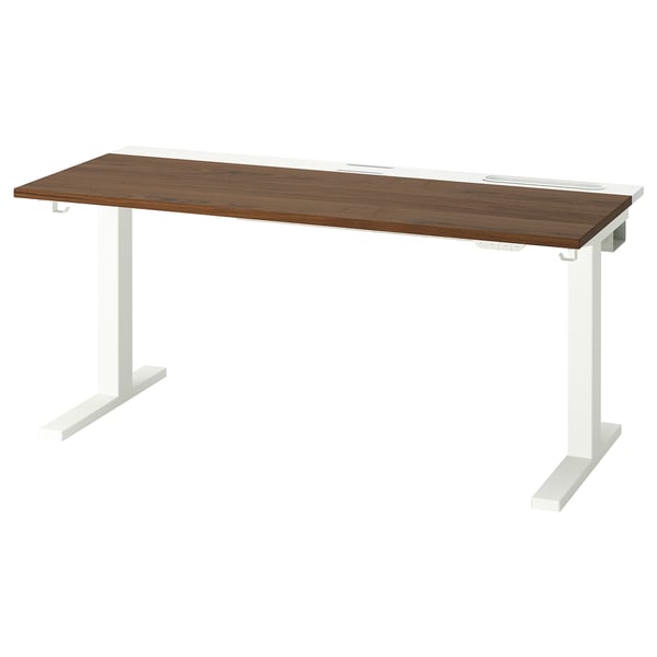 A MITTZON sit-stand desk with a dark wood top and white legs. It has an adjustable height feature and a built-in cable management tray.